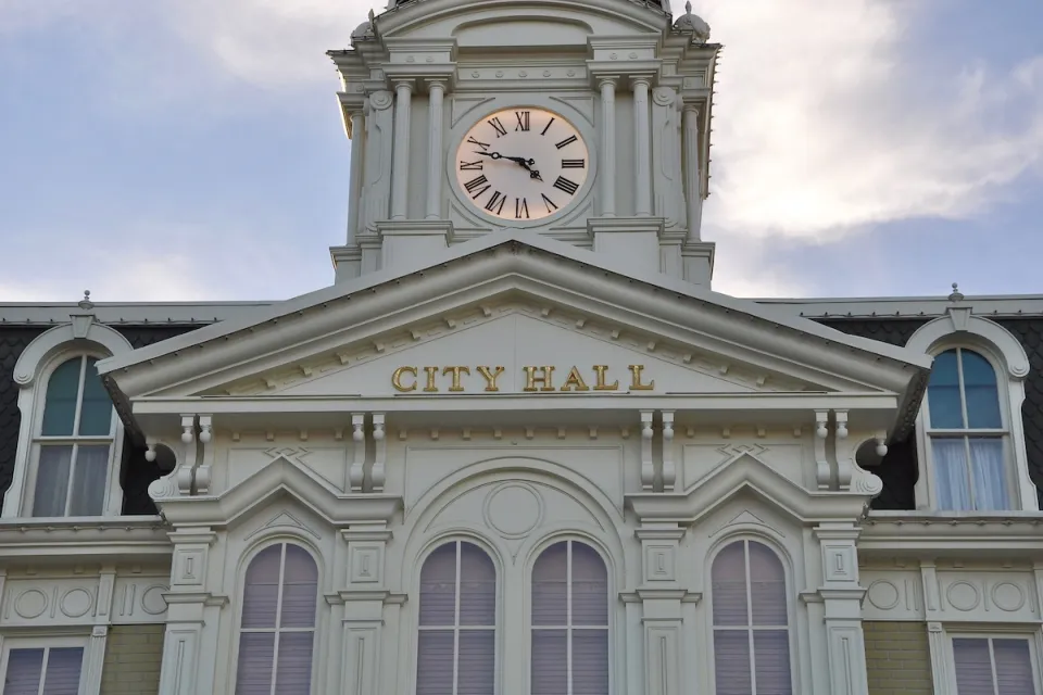 White neoclassical building with cupola and City Hall lettering on front.